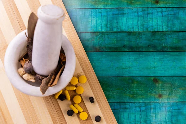 Arka planda mavi çizgili ahşap kesim tahtası ve toz için kurutulmuş otlar içeren havan topu. Ayurveda kavramı