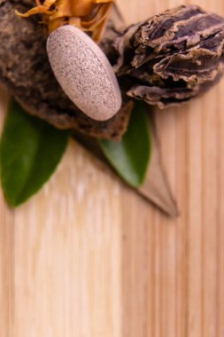 Kuru otlar ve ahşap arka planda yeşil yapraklarla düzenlenmiş bitkisel hap ve tabletlerin makro görüntüsü. Doğal ilaç konsepti