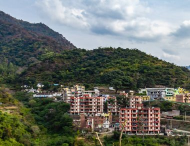 Bulutlu gökyüzünün altındaki dağın eteklerinde yer alan bina