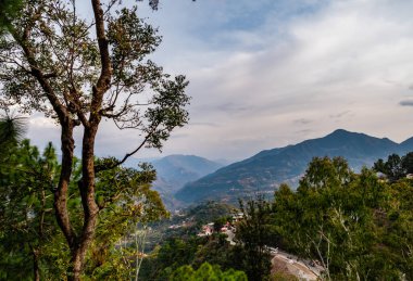Dağların güzel görüntüsü ve ön planda ağaçlar olan bulutlu mavi gökyüzü, doğa konsepti.