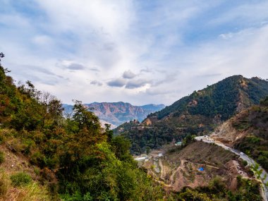 Bulutlu gökyüzünün altında yol boyunca ve dağ boyunca yüksek açılı tarla tipi ekin tarlası görüntüsü