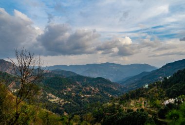 Bulutlu mavi gökyüzünün altında vadileri olan dağların arazi manzarası, doğa kavramı.