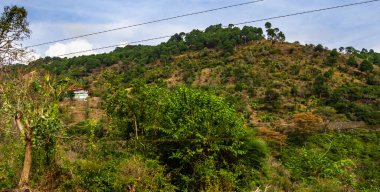 Tepedeki tepenin alçak açılı çekimi sol tarafında bir ev ve arka planda mavi gökyüzü, doğal konsept.