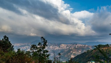 Dağlardaki evlerin fotoğrafları ve arka planda bulutlu mavi gökyüzü