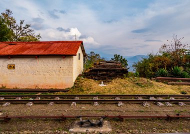 Demiryolu rayları boyunca tren penceresinin fotoğrafları ve arka planda bulutlu gökyüzü.