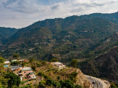 Doğal manzaranın geniş bir görüntüsü, dağ arkası ve ön planda evler, doğa koklanışı.