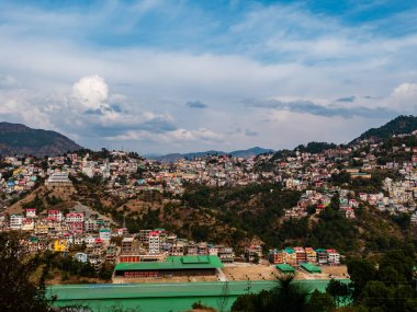 Bulutlu gökyüzünün altındaki dağlarda güzel şehir manzarasının geniş bir görüntüsü.