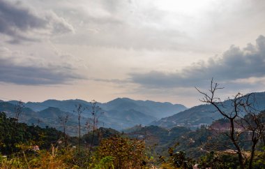 Geniş bir dağ manzarası ve arka planda bulutlu gökyüzü, doğa konsepti.