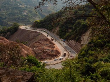 Arka planda tarımsal ekin tarlaları olan tepe boyunca geniş bir yol görüntüsü.