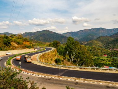 Geniş açılı bir yol. Kamyon engebeli tepeler ve arka planda bulutlu gökyüzü, ulaşım konsepti.