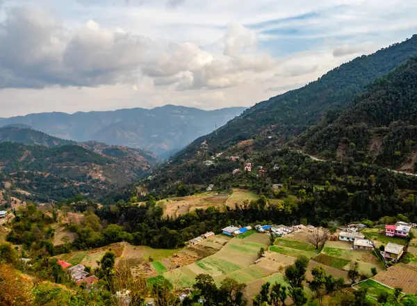 Teras tipi Corp Alanı. Köyde dağ eteklerinde az sayıda ev ve yukarıda bulutlu gökyüzü var.