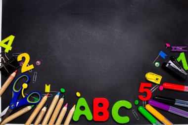 Siyah karatahtaya çok renkli kalemler ve kırtasiye malzemesi.