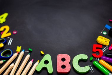 Siyah karatahtaya çok renkli kalemler ve kırtasiye malzemesi.