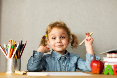 Şirin Avrupalı kız okul masasında oturuyor, öğrenme konsepti, okula geri dönüyor.