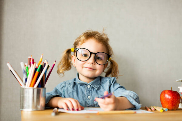 Cute European girl sits at school desk, concept of learning, back to school