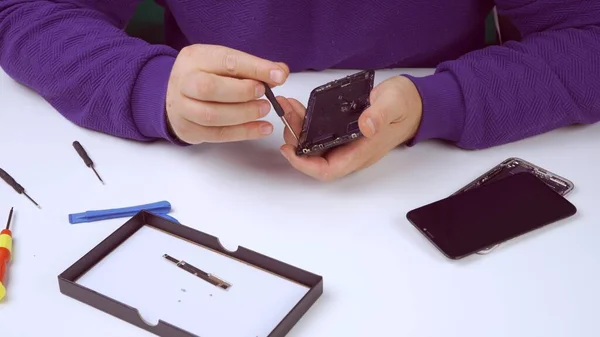 Phone repairman repairing a smartphone via warranty