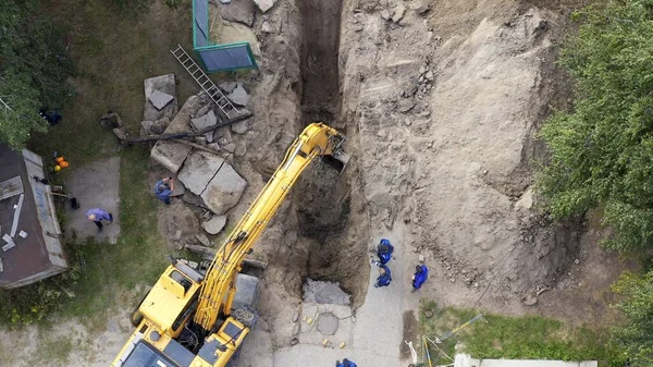 Excavator and workers digging a pipe hole
