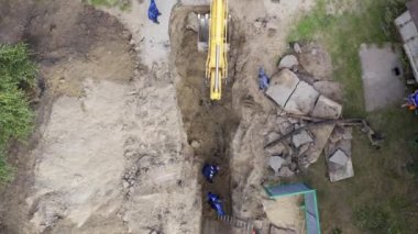 Kazıcı ve işçiler bir boru çukuru kazıyor