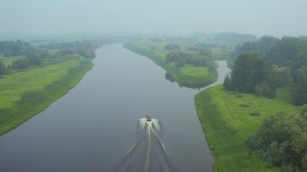 Ein Motorboot treibt im Morgennebel auf dem Fluss — Stockvideo