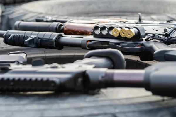 Un fusil de chasse avec des munitions et des armes automatiques se trouvent sur une roue de voiture. Concept de guerre, organisations militaires privées — Photo