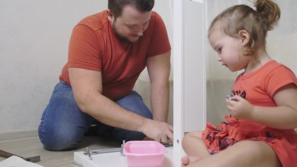 Papá y su hija recogen muebles de aglomerado. Papá y la muchacha recogen los muebles caseros juntos . — Vídeos de Stock