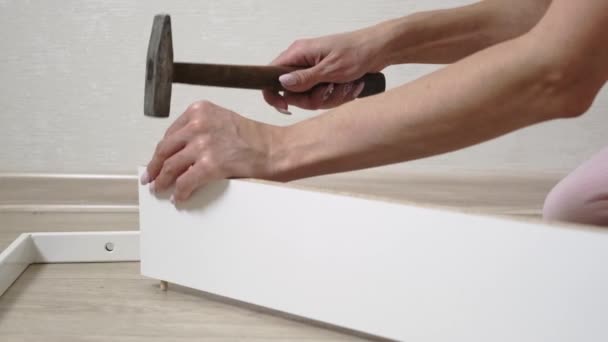 A woman collects boxes from chipboard with a hammer — Stock Video