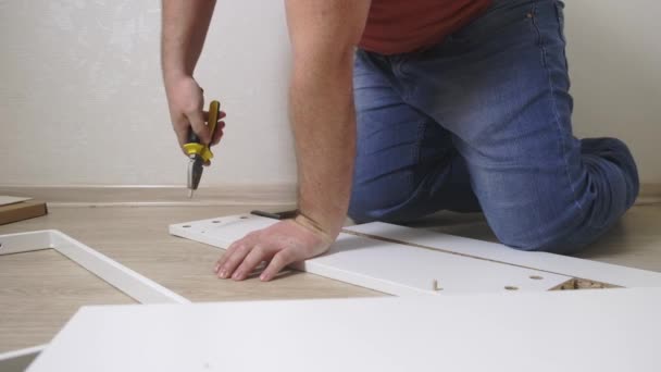 Man collects boxes from chipboard with a screwdriver — Stock Video