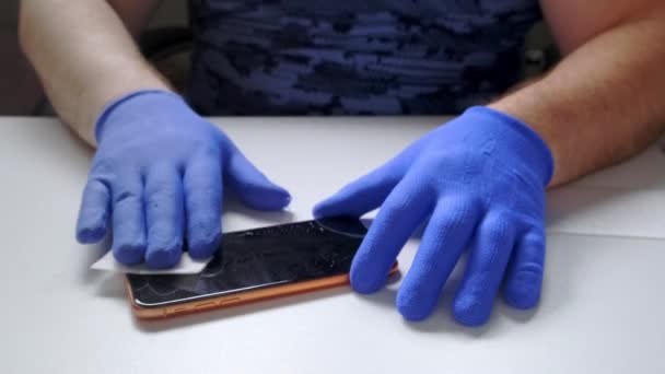 Een mannelijke hand vervangt een gebroken schermbeschermer van gehard glas voor een smartphone. — Stockvideo