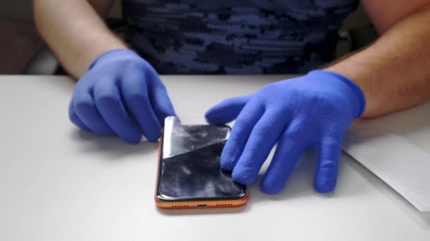 En manlig hand ersätter en trasig härdat glas skärmskydd för en smartphone. — Stockvideo