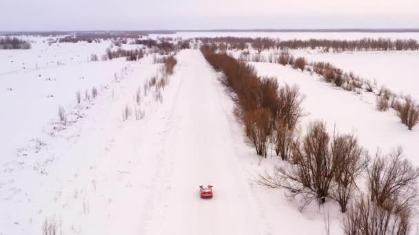 Pomarańczowy samochód na zimowej śnieżnej drodze, widok z góry. — Wideo stockowe