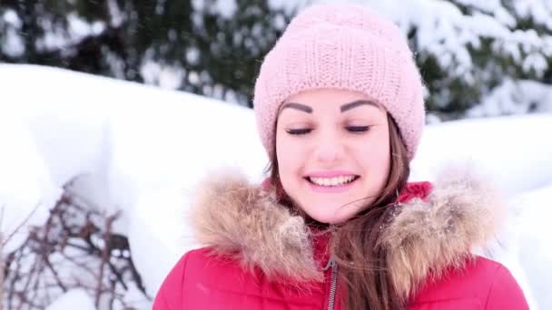 Cheerful young woman is drinking takeaway coffee while walking in winter, falling snow. — Stock Video