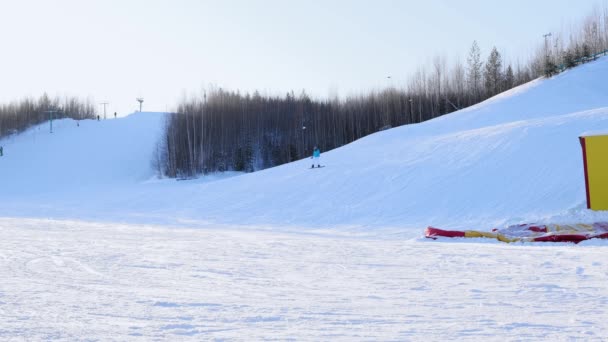 Esquiadores y snowboarders montando en una estación de esquí en una montaña nevada de invierno con vista panorámica de fondo — Vídeos de Stock