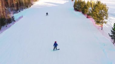 Kış günü bir dağ yamacında snowboardcu geziyor.