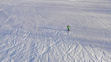 Kış günü bir dağ yamacında snowboardcu geziyor.