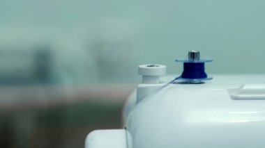 The thread is unwrapped from the coil of the sewing machine