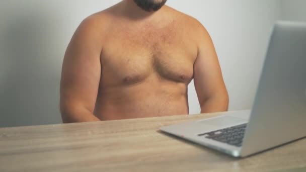 Dicker Mann knackt seine fetten Brüste, wenn er am Computer sitzt. — Stockvideo