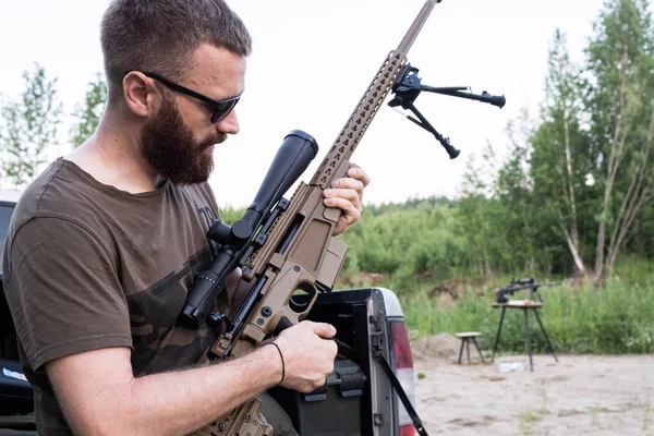 Un homme à lunettes avec une barbe tient un fusil de sniper — Photo