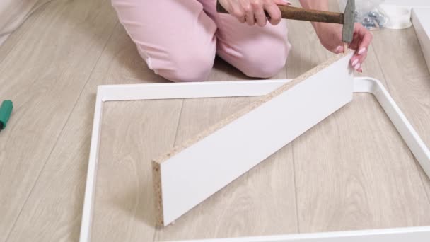 Eine Frau sammelt mit dem Hammer Kisten aus Spanplatten — Stockvideo