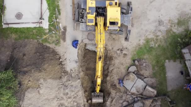 Экскаватор и рабочие копают яму для труб — стоковое видео