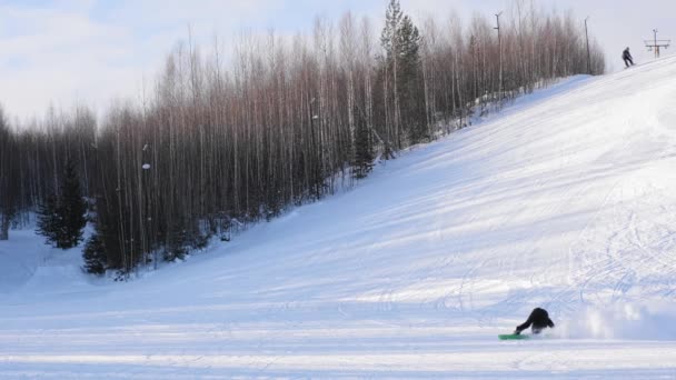 Snowboardzista spada na zbocze góry, daleki plan — Wideo stockowe