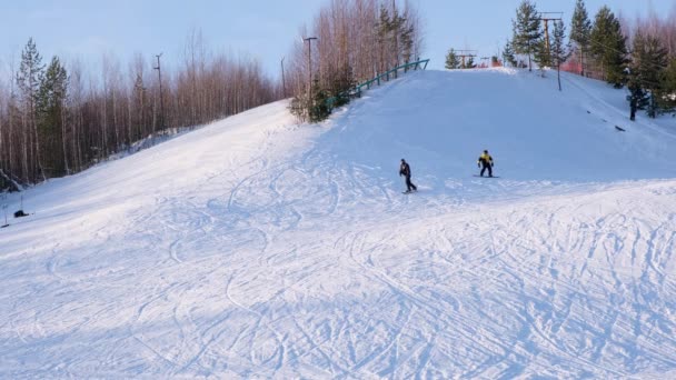 滑雪者和滑雪者乘坐雪地冬季山上的滑雪场，背景景色宜人 — 图库视频影像