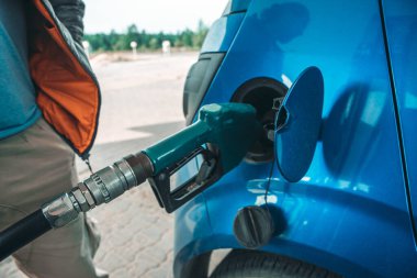 Benzin dolum tabancası, benzin istasyonundaki mavi bir arabanın tankına yerleştirilir..