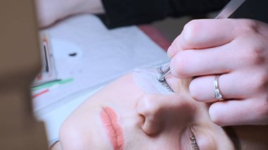 Kadına yapay kirpikler yapıştırmak. Kozmetik işlem