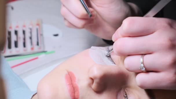 Sticking artificial eyelashes to the woman. Cosmetic procedure — Stock Video