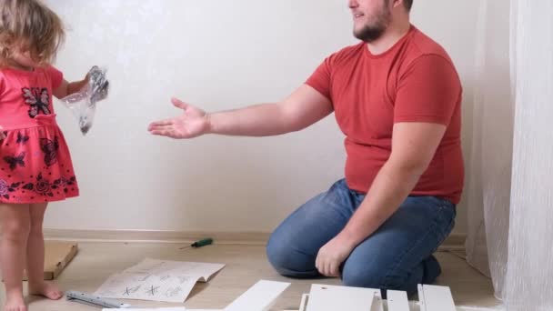 Dad and daughter collect furniture from chipboard. Dad and girl collect home furniture together. — Stok video