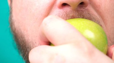 Sakallı şişman bir adam yeşil bir elma yer. Yakın plan.