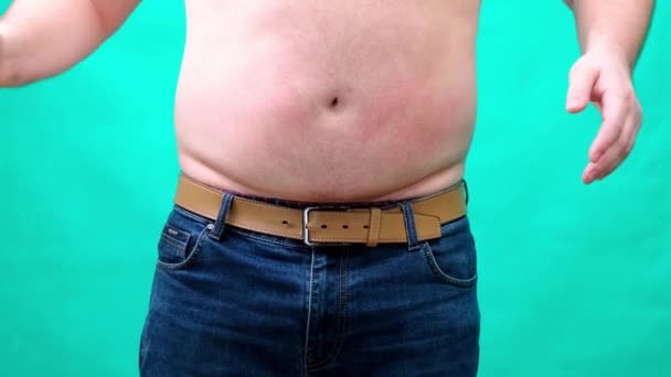Мужчина показывает большой жирный живот на экране. Избыточный вес и переедание проблема. Закрыть 4K — стоковое видео