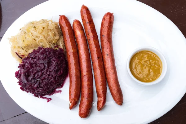 Klasszikus német snack, kolbász mustáros káposztával és bagellel fehér tányéron — Stock Fotó