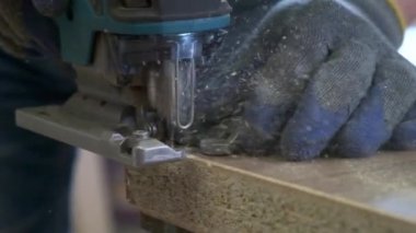 Profesyonel marangoz mobilya yapıyor, yavaş çekimde değirmen makinesiyle masanın kenarını düzleştiriyor.