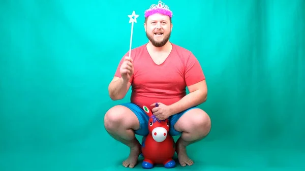 Funny video, a freak man on a small pink horse with a magic wand on a green background